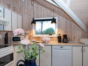 A kitchen with wooden walls, a window, and a vase with flowers.