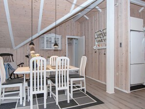 A dining area with a table, chairs, and a ceiling with exposed beams.