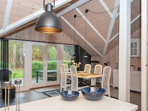 A dining area with a table, chairs, and a large window overlooking a garden. - 6 Person Holiday Home in Hemmet (Hemmet)