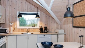 Una cocina compacta con paredes de madera, una ventana, un lavabo, un microondas, una cafetera y un tostador.