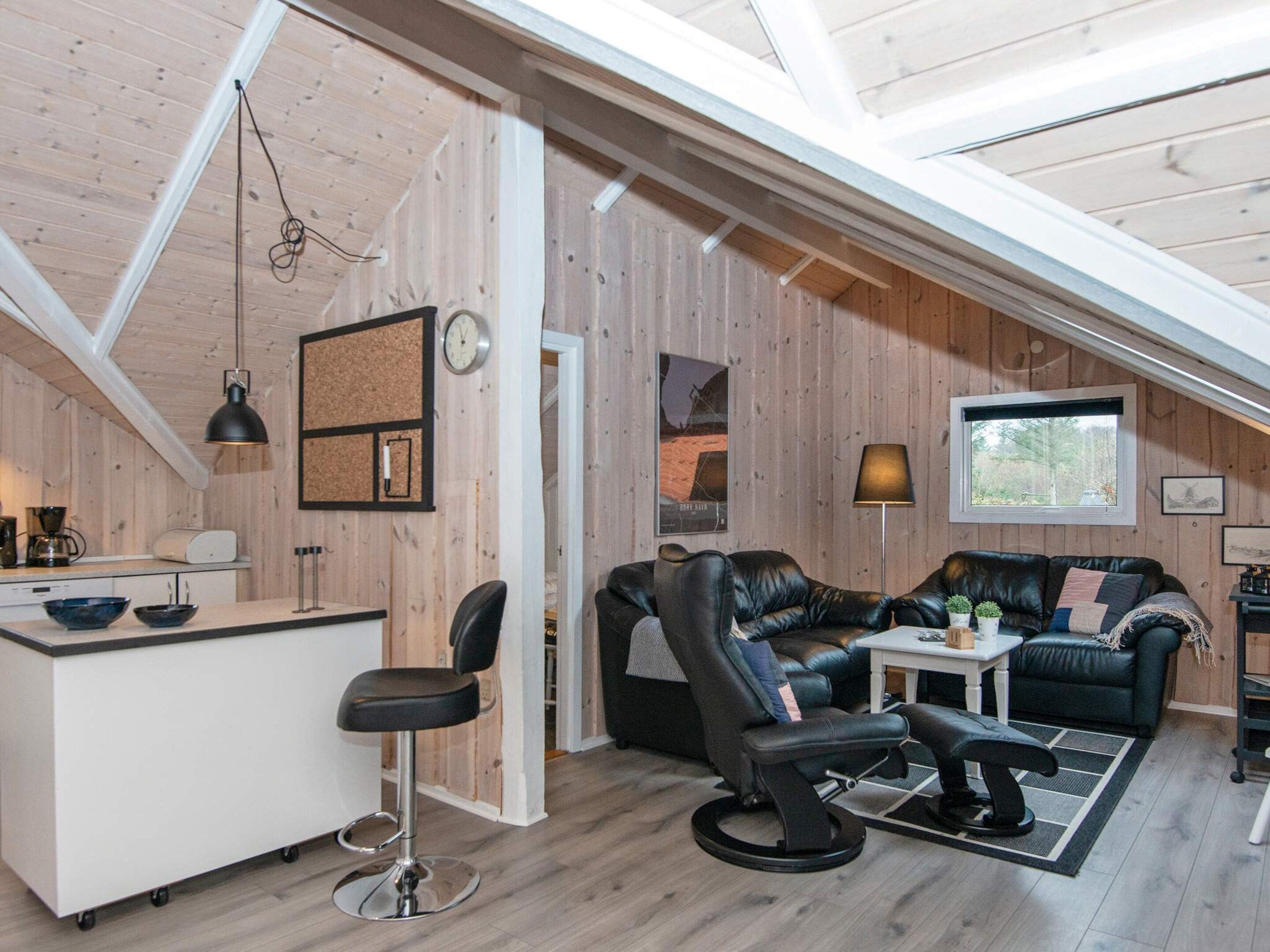 A loft-style room with a kitchen area, a dining table, a sofa, and a chair.