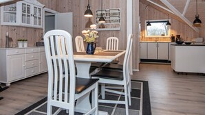 Una cocina moderna con armarios blancos, un comedor con sillas blancas y una isla central.