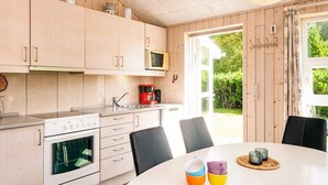 Ett modernt kök med träskåp, en mikrovågsugn, en kaffebryggare och en matplats med ett bord och stolar.