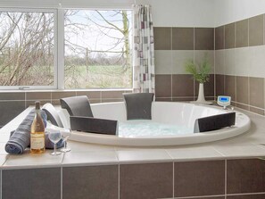 A modern bathroom with a large bathtub, a window with a view of trees, and a potted plant. - Holiday Home in Kappeln (Kappeln)