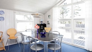 A modern dining area with a round table, four chairs, and a flag. - 8 Person Holiday Home in Blavand (Blavand)