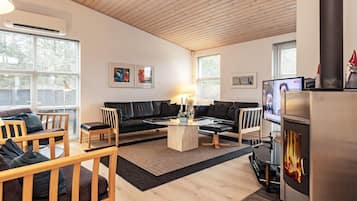 En moderne stue med pejs, lædersofaer, træstole og kunst på væggene.