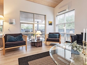 A modern living room with two sofas, a glass coffee table, and large windows with blinds. - 5 Star Holiday Home in Lokken (Lokken)