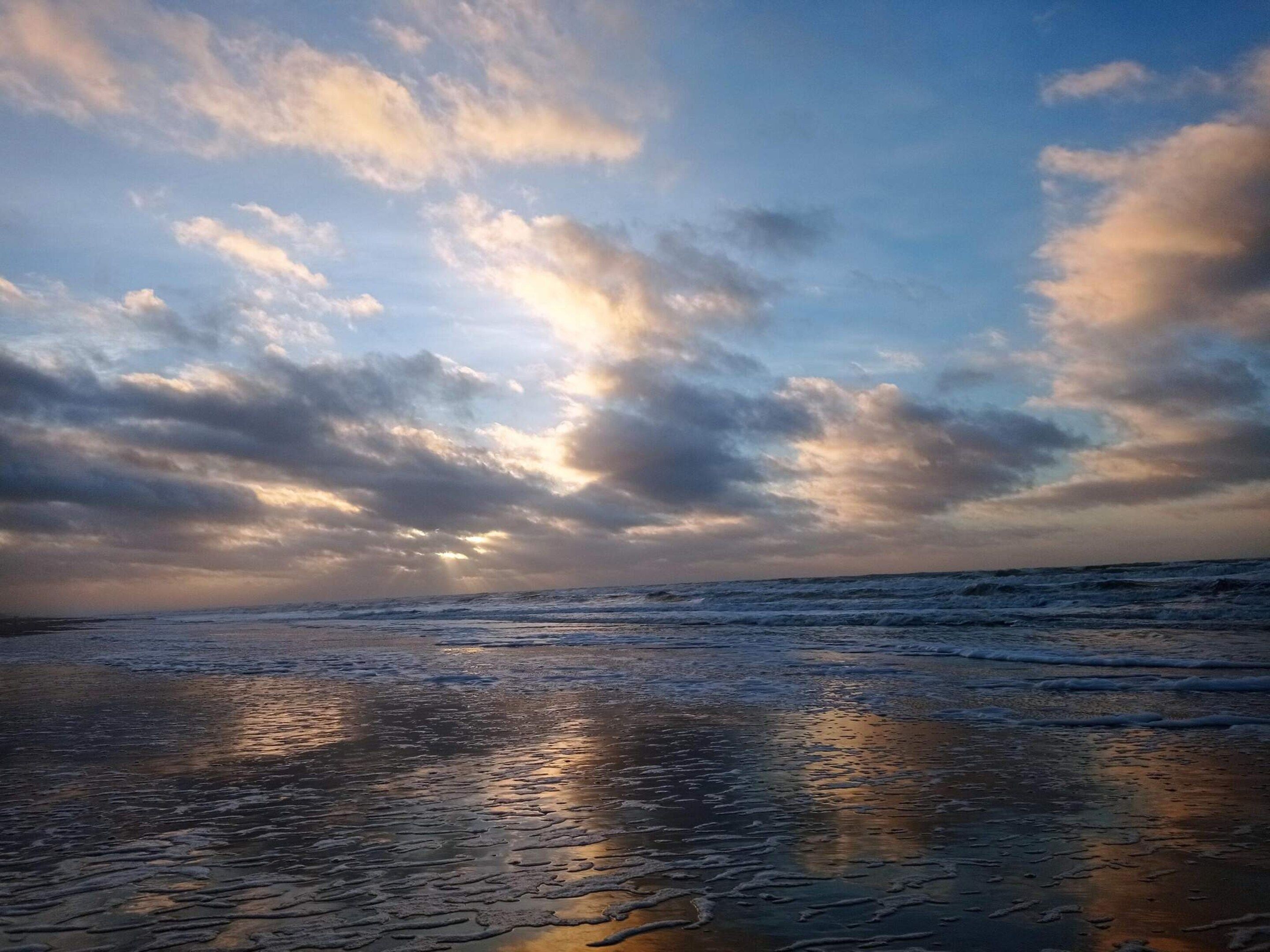 En strand med bølger og en overskyet himmel.