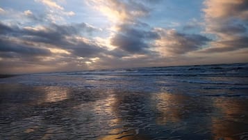 En strand med bølger og en overskyet himmel.