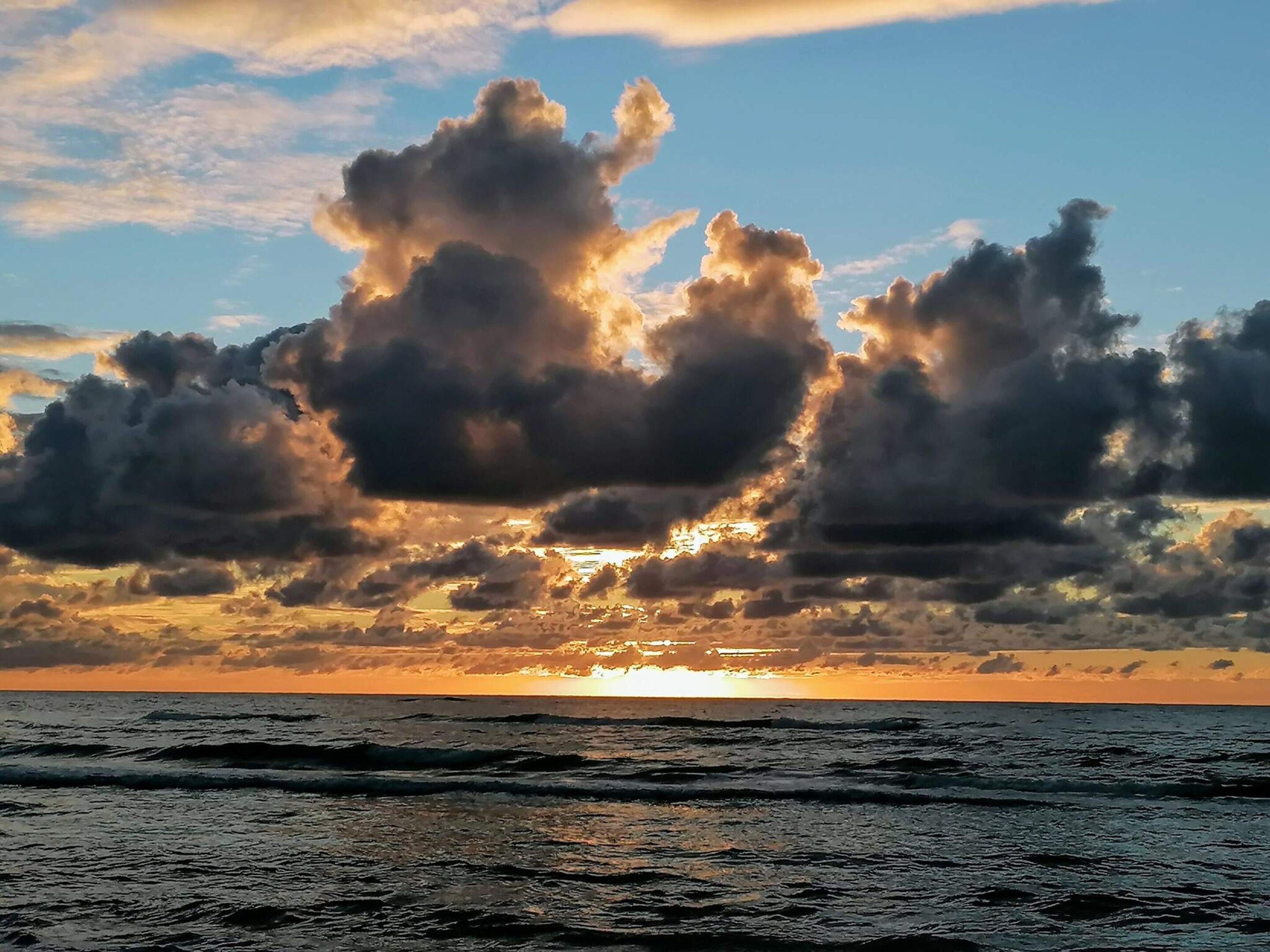 A sunset over the ocean with clouds.