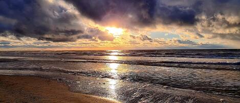 A beach with waves and a sunset.