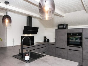 A modern kitchen with a built-in oven, a microwave, a sink, and a large island.