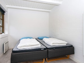 A small, enclosed room with two beds, a window, and a radiator. - 12 Person Holiday Home in Henne (Henne)