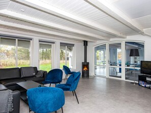 A modern living room with a fireplace, a sofa, chairs, and a television. - 12 Person Holiday Home in Henne (Henne)