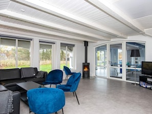 A modern living room with a fireplace, a sofa, chairs, and a television.