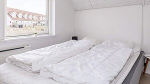 A bedroom with two beds, a window with a view of houses, and a white ceiling. - 6 Person Holiday Home in Thisted-by Traum (Thisted)