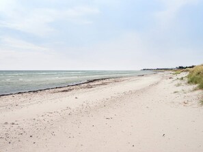 A sandy beach with a clear sky and calm sea.
