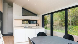 A modern kitchen with white cabinetry, a built-in microwave, and a large window overlooking a garden.