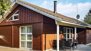 A wooden house with a covered patio, a chimney, and a satellite dish. - 6 Person Holiday Home in Laeso (Læsø)