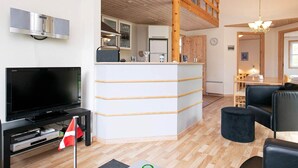 A modern living room with a TV, a kitchen area, and a dining space. - 6 Person Holiday Home in Laeso (Læsø)