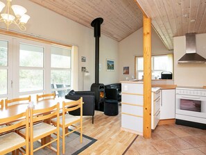 A cozy interior with a dining area, a black sofa, a kitchen with a stove, and a large window.