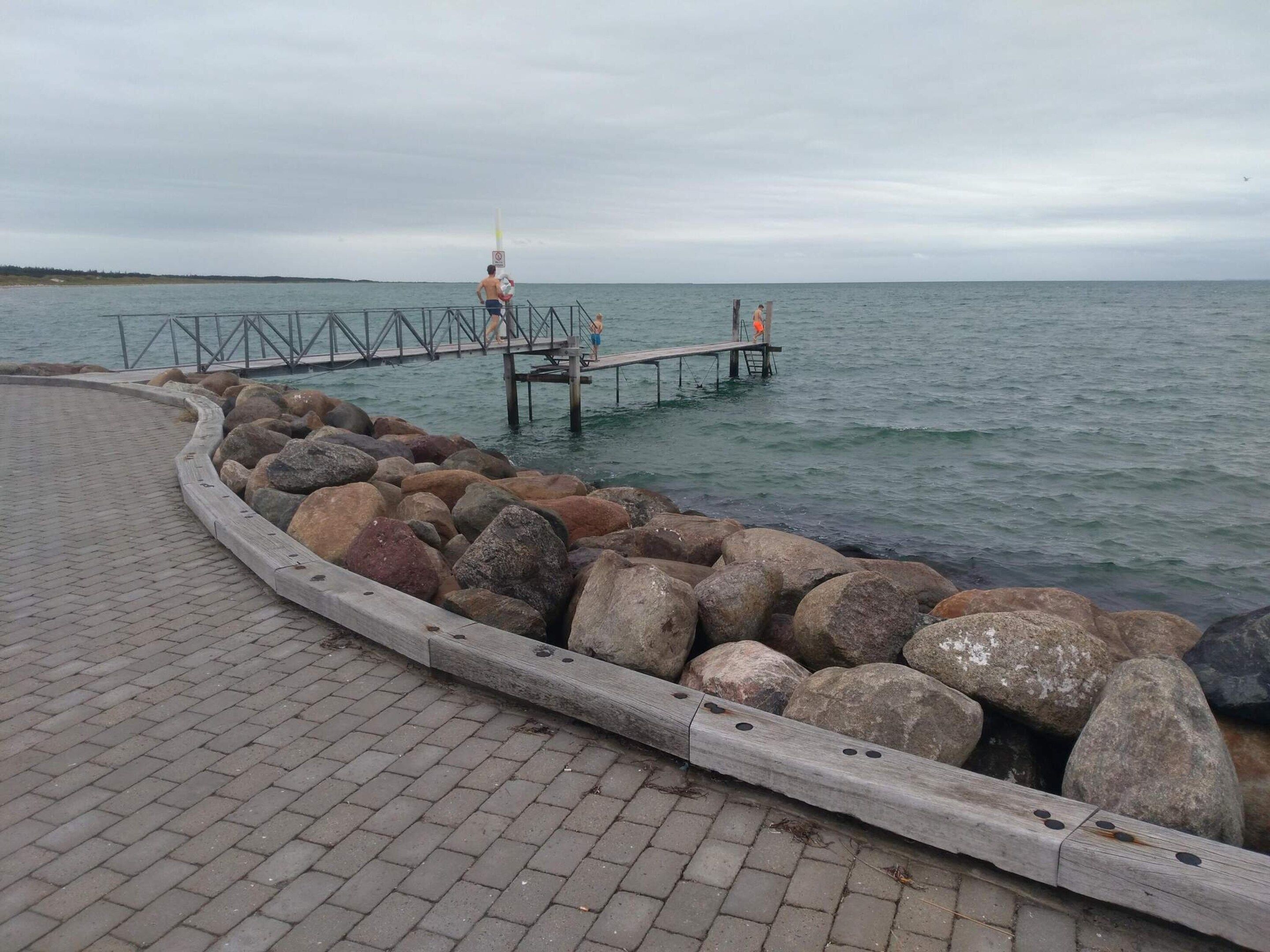 A paved walkway with a wooden railing and large rocks.