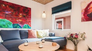 Ein modernes Wohnzimmer mit einem Ecksofa, einem runden Holztisch und einem großen abstrakten Gemälde.