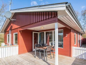 Une maison en bois rouge avec un patio couvert, une antenne parabolique et le chiffre « 2 » peint sur le côté.