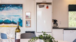 Eine Küche mit einem weißen Kühlschrank, einem Bosch Geschirrspüler, einem Gemälde von Wellen und einem Blumentopf auf dem Tisch.
