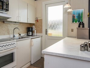 A compact kitchen with a stove, sink, and coffee maker.