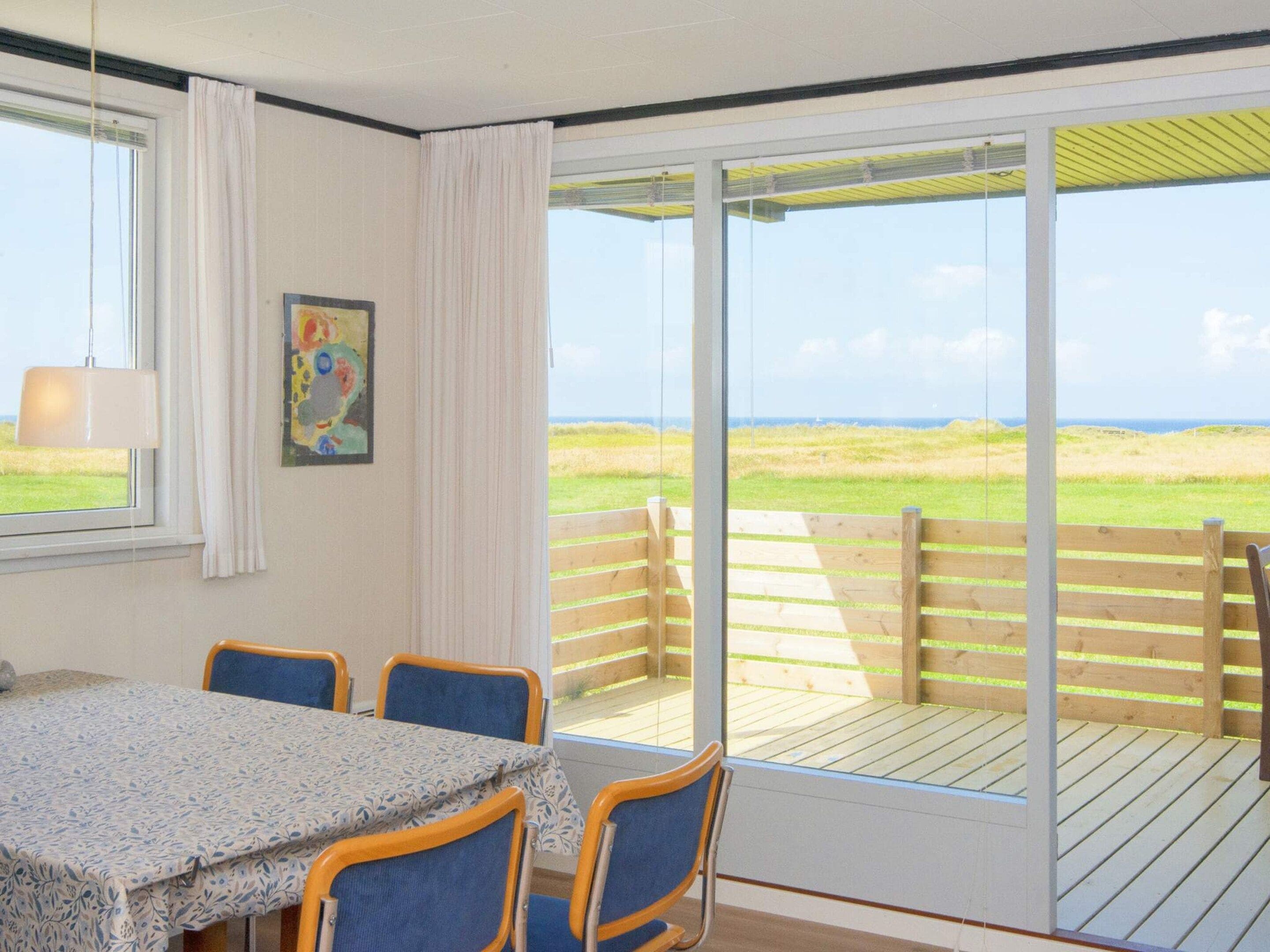 Una habitación con una mesa y sillas, un cuadro en la pared y vistas al exterior a través de una puerta corredera.