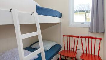 Una cama litera con escalera, dos sillas rojas y una ventana con vista a un edificio.