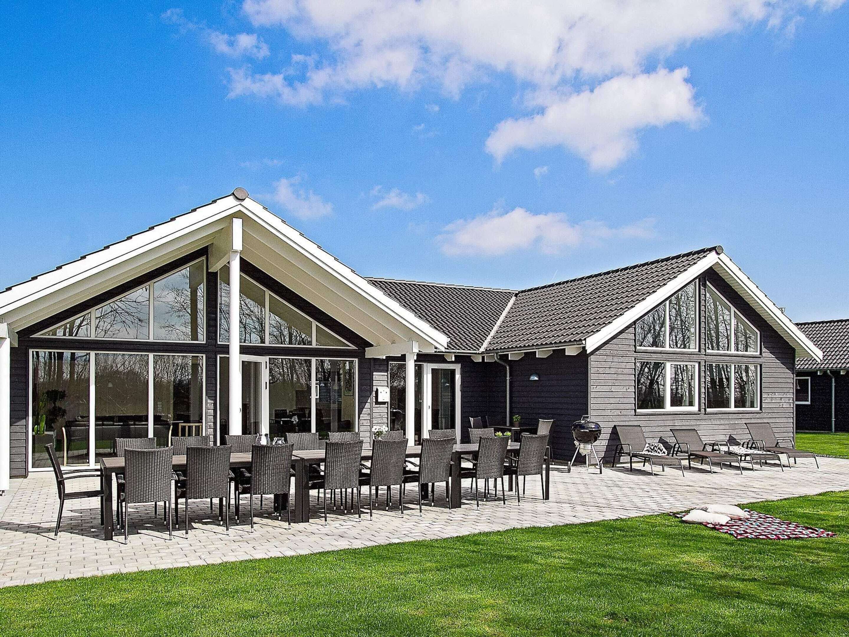A modern house with a patio, large windows, and outdoor seating.