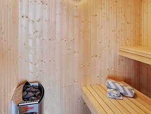 Een sauna met een Harvia Vega sauna, een houten bank en handdoeken.