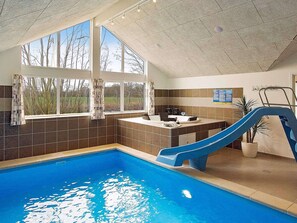 Une piscine intérieure avec un toboggan, une fenêtre avec des rideaux et un comptoir avec un évier.
