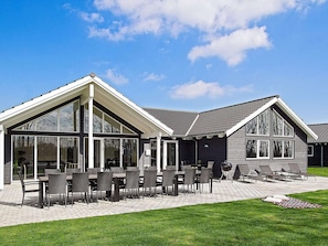 A modern house with a patio, large windows, and outdoor seating.