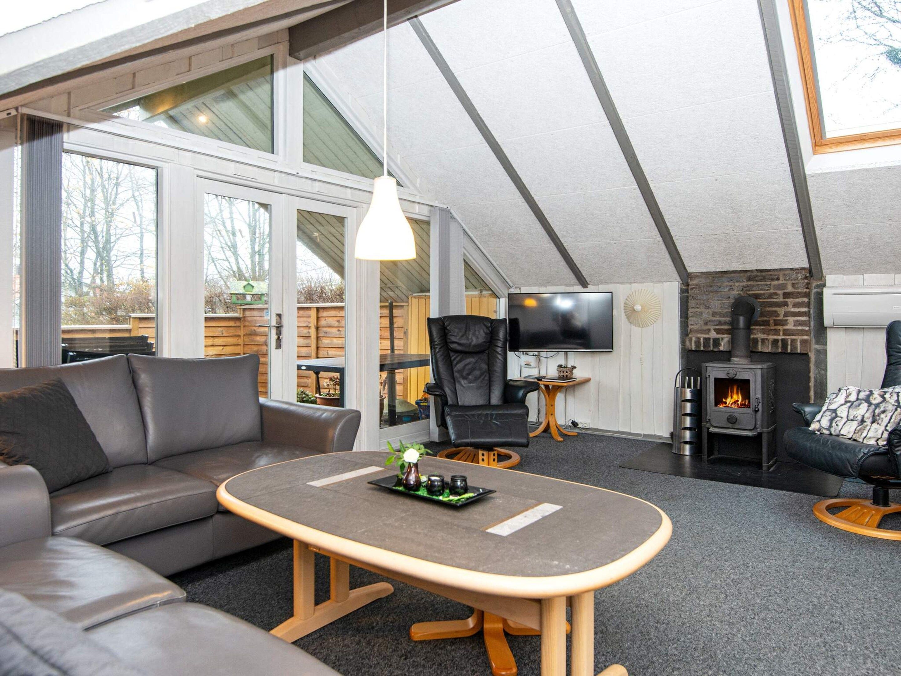 A modern living room with a sofa, a small table, a TV, and a fireplace.