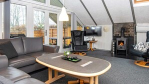 En moderne stue med sofa, lille bord, fjernsyn og pejs.