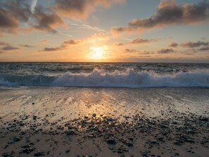 A beach with waves at sunset, pebbles, and a clear sky. - Modish Holiday Home in Jutland near Sea (Harboore)
