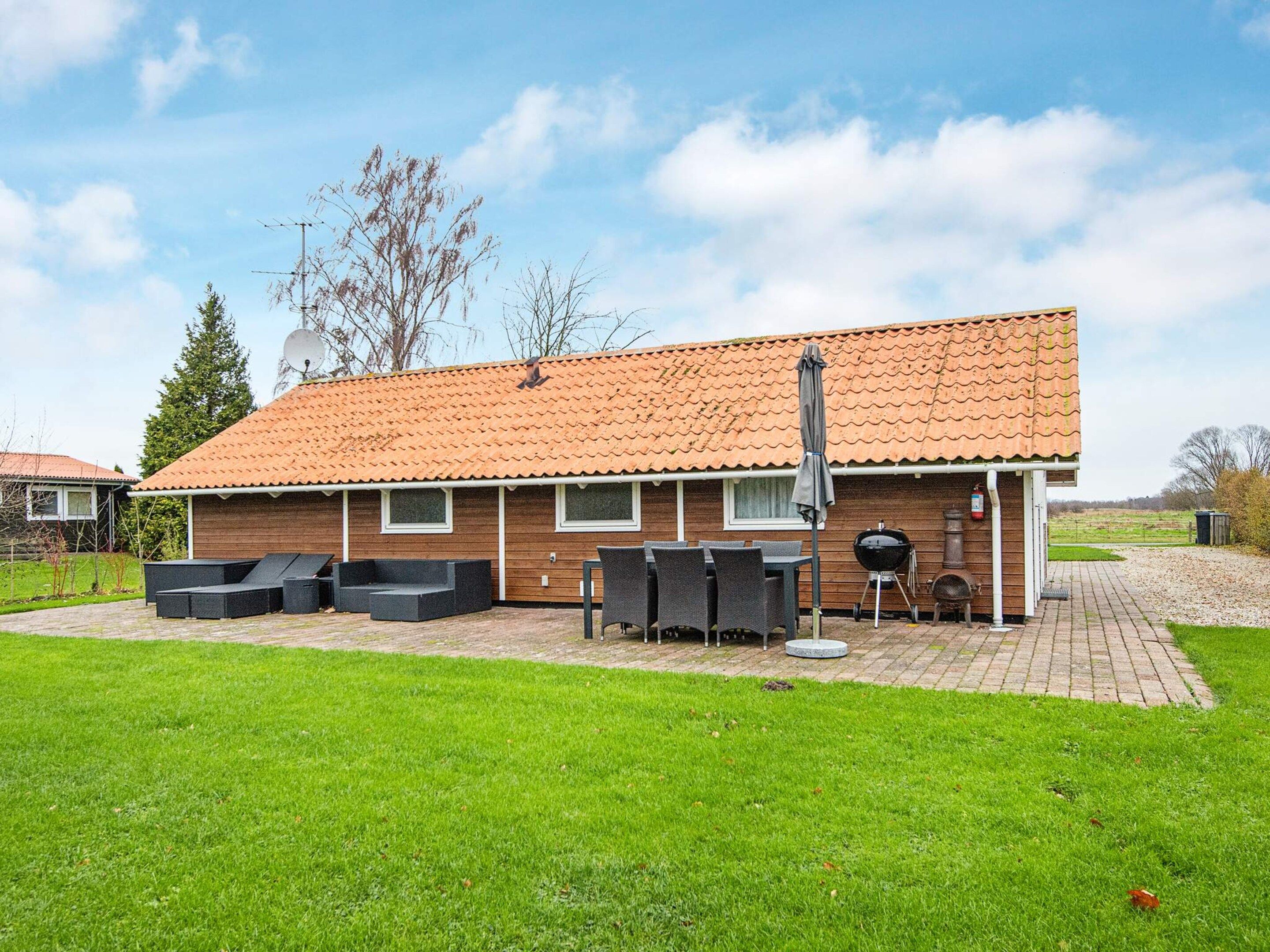 A house with a tiled roof, a patio with outdoor furniture, and a barbecue grill.
