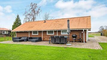 A house with a tiled roof, a patio with outdoor furniture, and a barbecue grill.