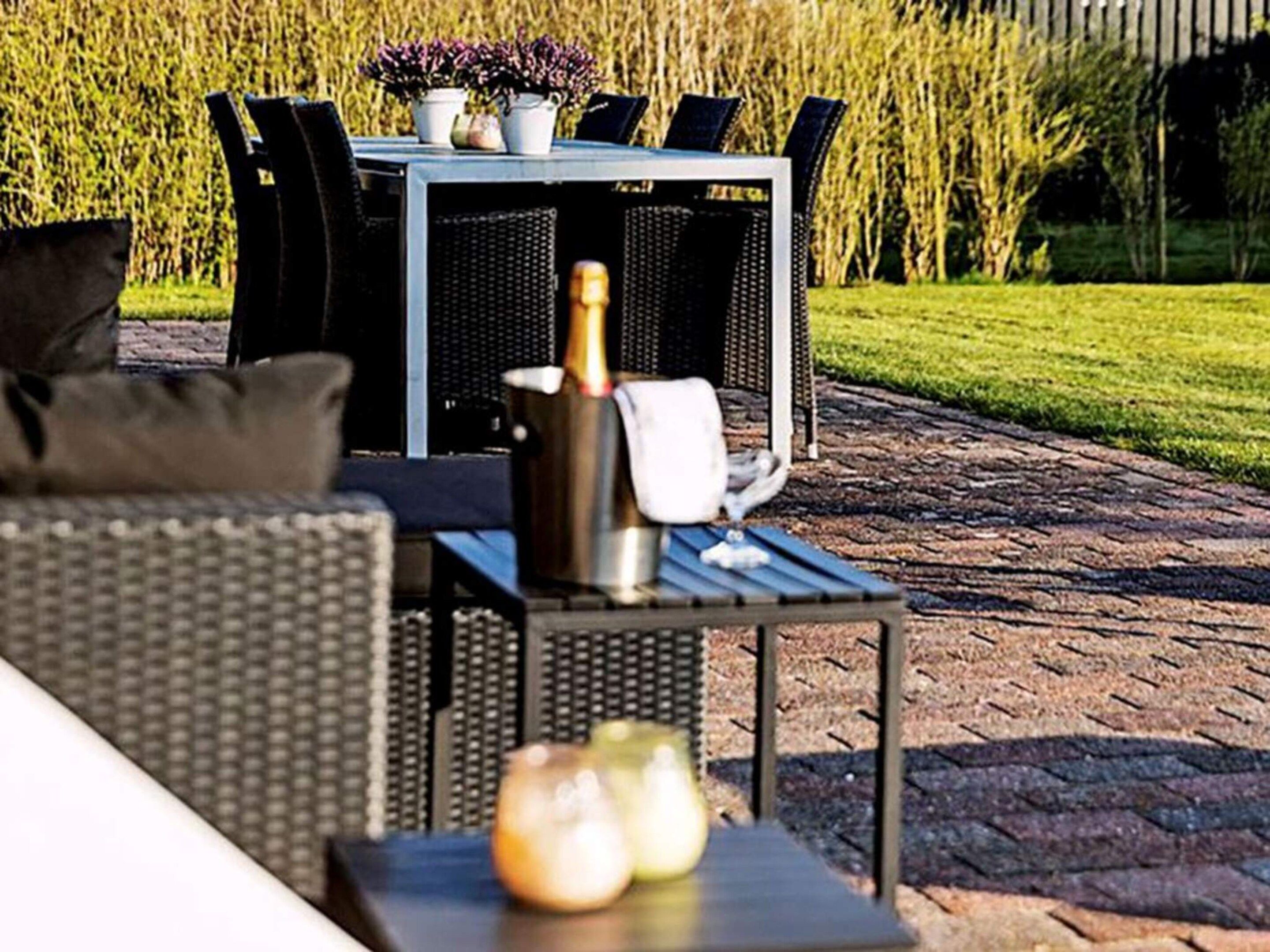 Ein Sitzbereich im Freien mit Tisch und Stühlen, einer Champagnerflasche und einer Kerze.