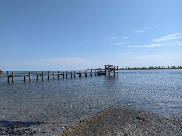 Eine Holzstele ragt in ruhiges Wasser, am Ende liegt ein kleines Boot festgemacht.