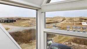 Ett rum med stora fönster som erbjuder utsikt över ett lantligt landskap, en väg och en byggnad i fjärran.