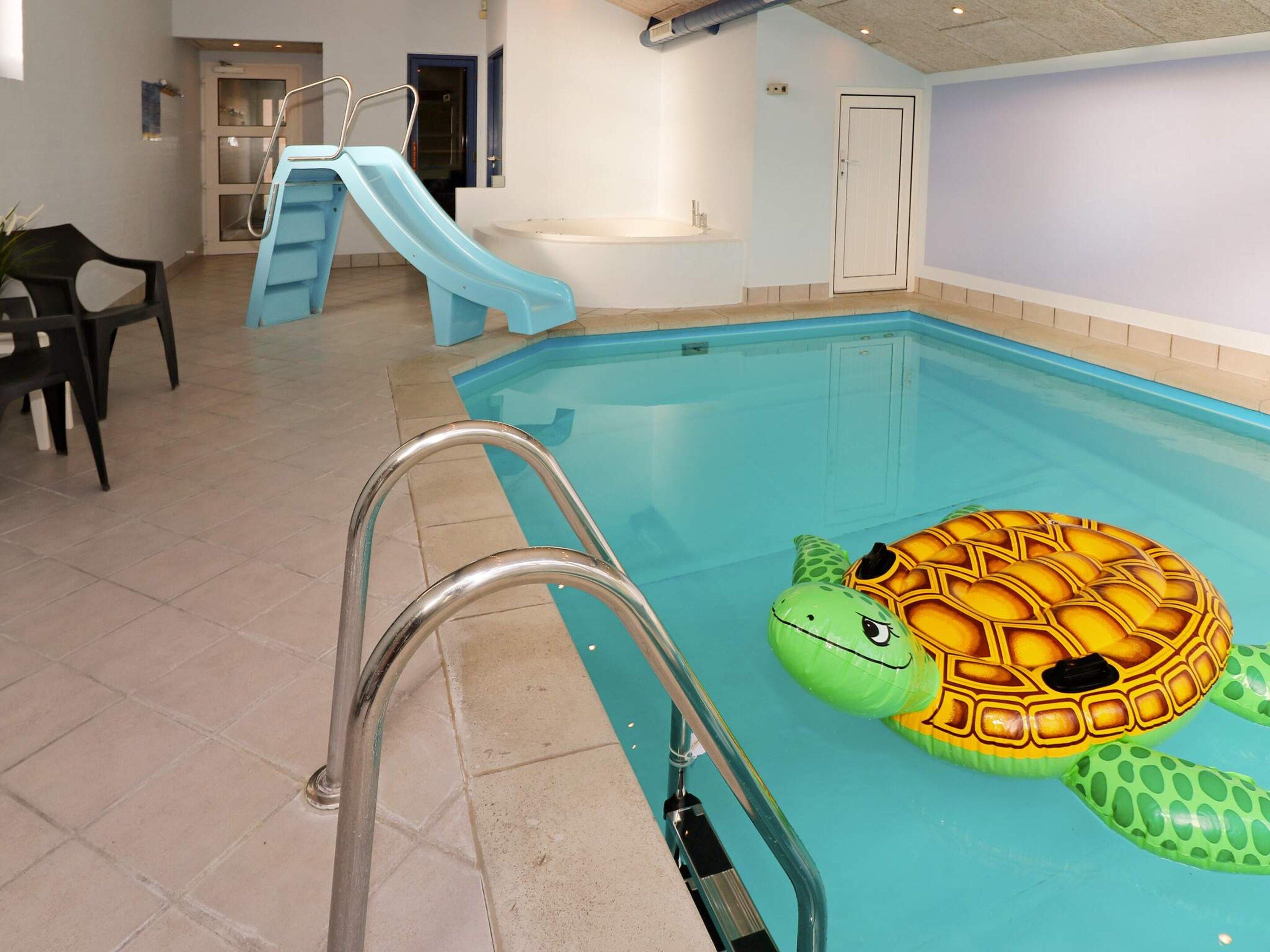 En indendørs swimmingpool med rutsjebane, en redningsplatform og en badedragon.