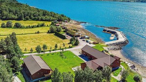 Järvenrantatontti, jossa on useita rakennuksia, laituri ja näkymä järvelle ja vuorille.