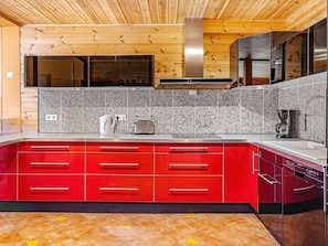 A modern kitchen with red cabinetry, granite backsplash, stainless steel appliances, and a wooden ceiling. - Holiday Home in EidsvÃ¥g (Molde)