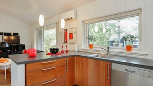 A modern kitchen with wooden cabinets, a black countertop, and a built-in dishwasher. - Peaceful Holiday Home in Nordjylland With Sauna (Læsø)