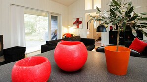 A modern living room with a black sofa, a red vase, and an orange pot with a plant. - Peaceful Holiday Home in Nordjylland With Sauna (Læsø)