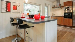 A modern kitchen with a central island, bar stools, and a built-in oven. - Peaceful Holiday Home in Nordjylland With Sauna (Læsø)
